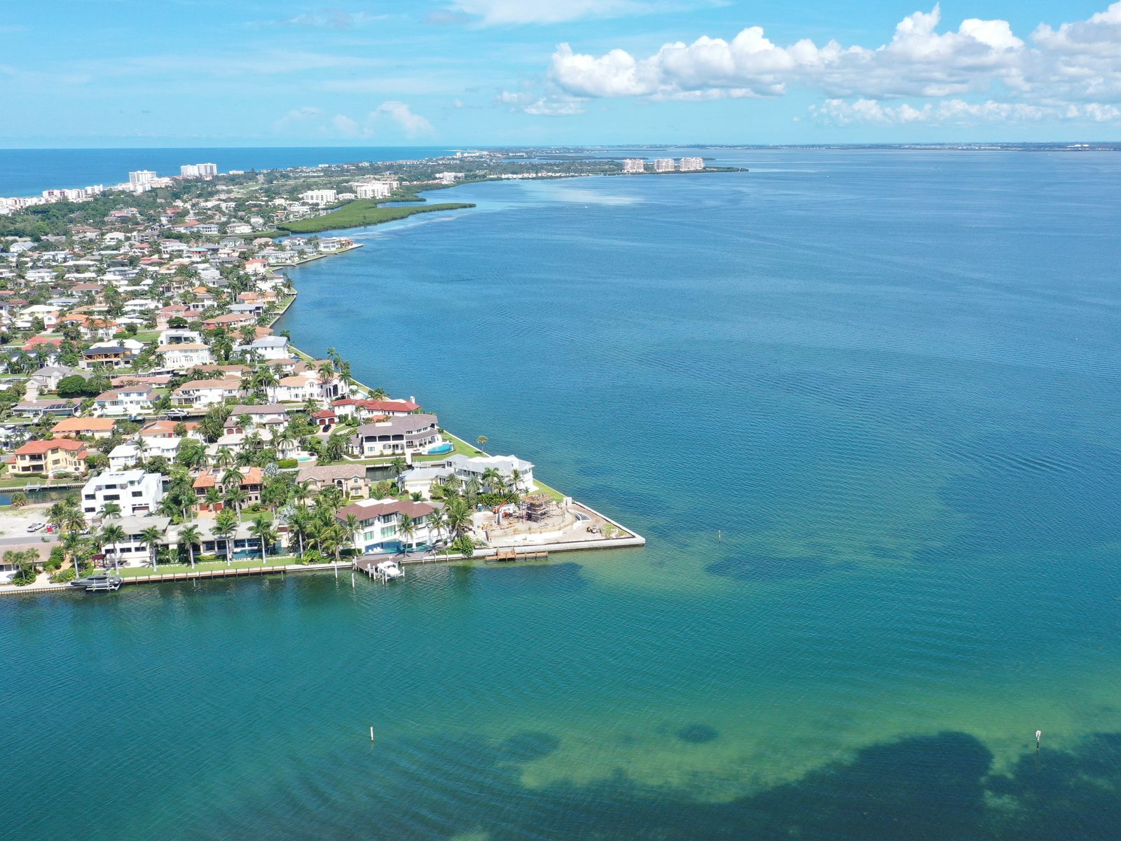 Aerial over Country Club Shores: canal-front homes and the open-bayfront point lots reaching into Sarasota Bay