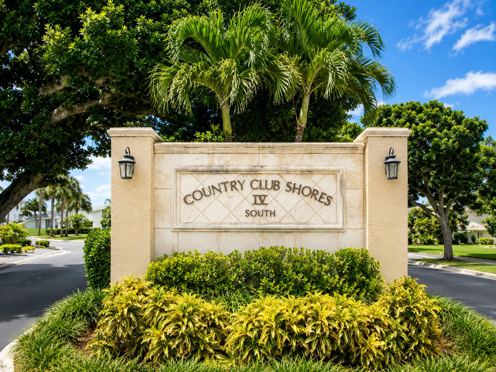 The Country Club Shores IV South entrance monument on Longboat Key, palms and mature canopy behind it