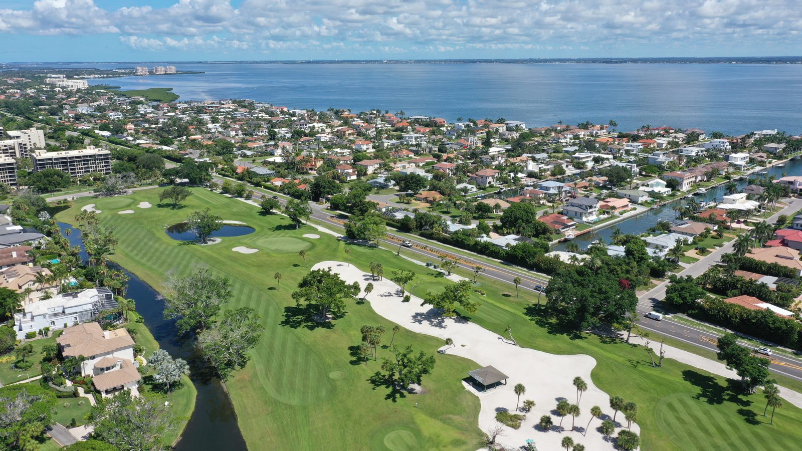 Wide aerial of Country Club Shores: the golf course across Gulf of Mexico Drive, the canal grid, and Sarasota Bay beyond